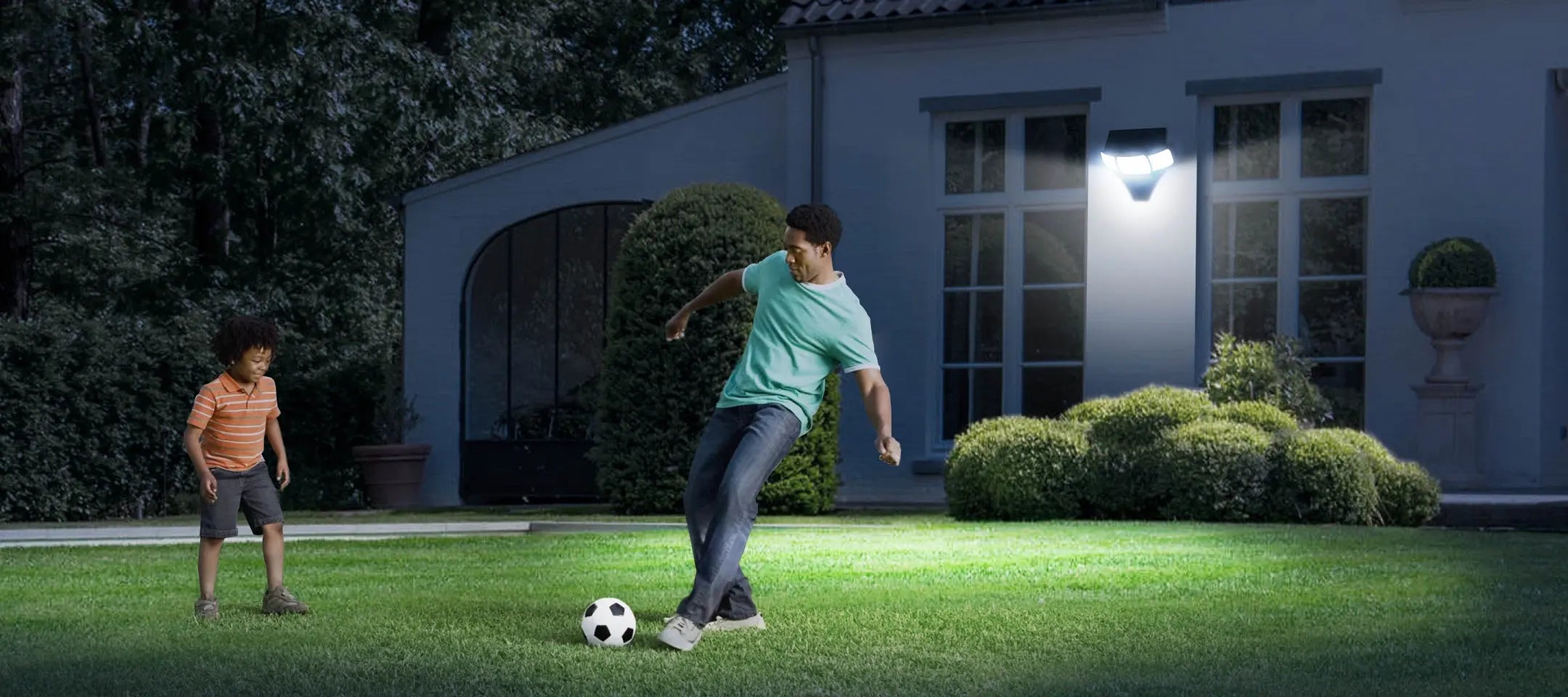 intelamp 3‑head solar motion sensor outdoor flood light lighting residential backyard lawn, father and son playing soccer at night, IP65 waterproof solar security light for yard patio driveway