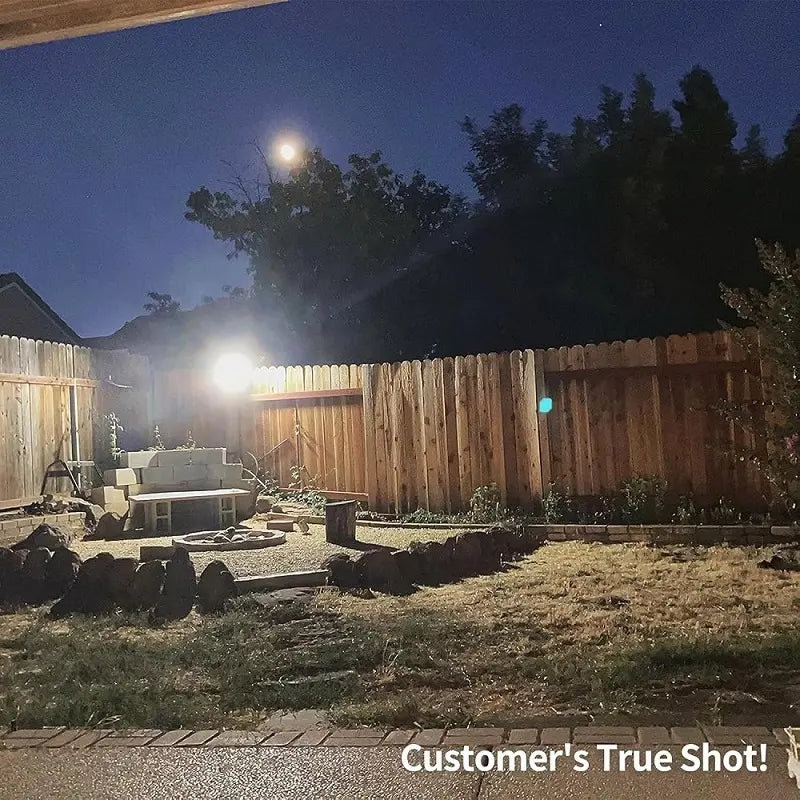 Customer true shot demonstrating the bright 3000LM illumination of Intelamp outdoor solar flood lights lighting up a backyard fence at night.
