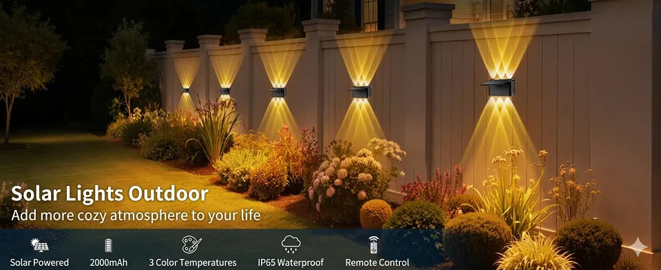 Row of elegant warm white solar up and down lights illuminating a garden fence, creating a cozy atmosphere